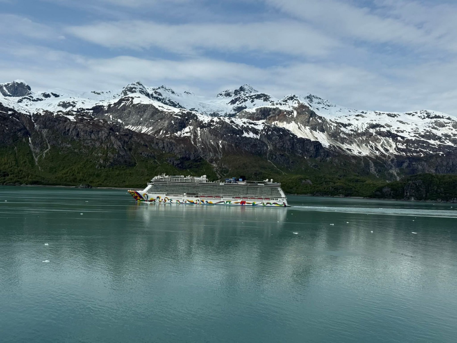 A cruise ship sailing beneath snow-covered mountains in Alaska, photographed by Gina Renée