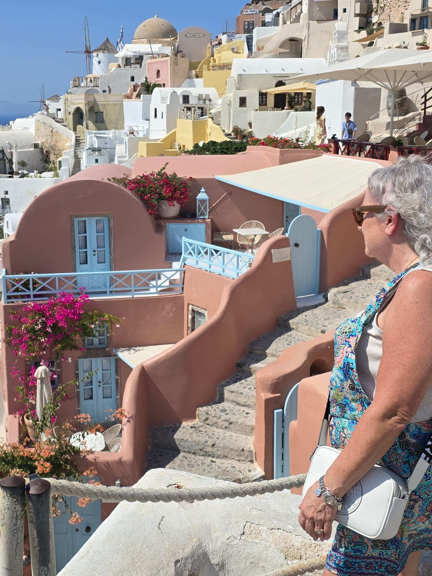 Gina Renée overlooking the colorful cliffside homes of Santorini, Greece